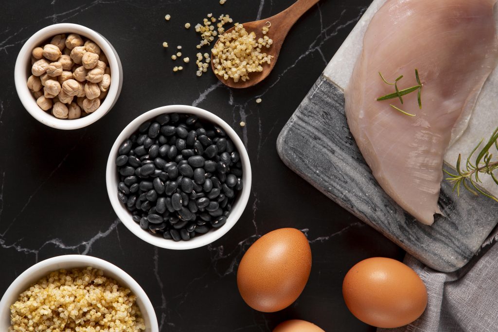 Multiple different sources of protein including chicken, black beans, eggs, quinoa, protein powder and more. Image by freepik